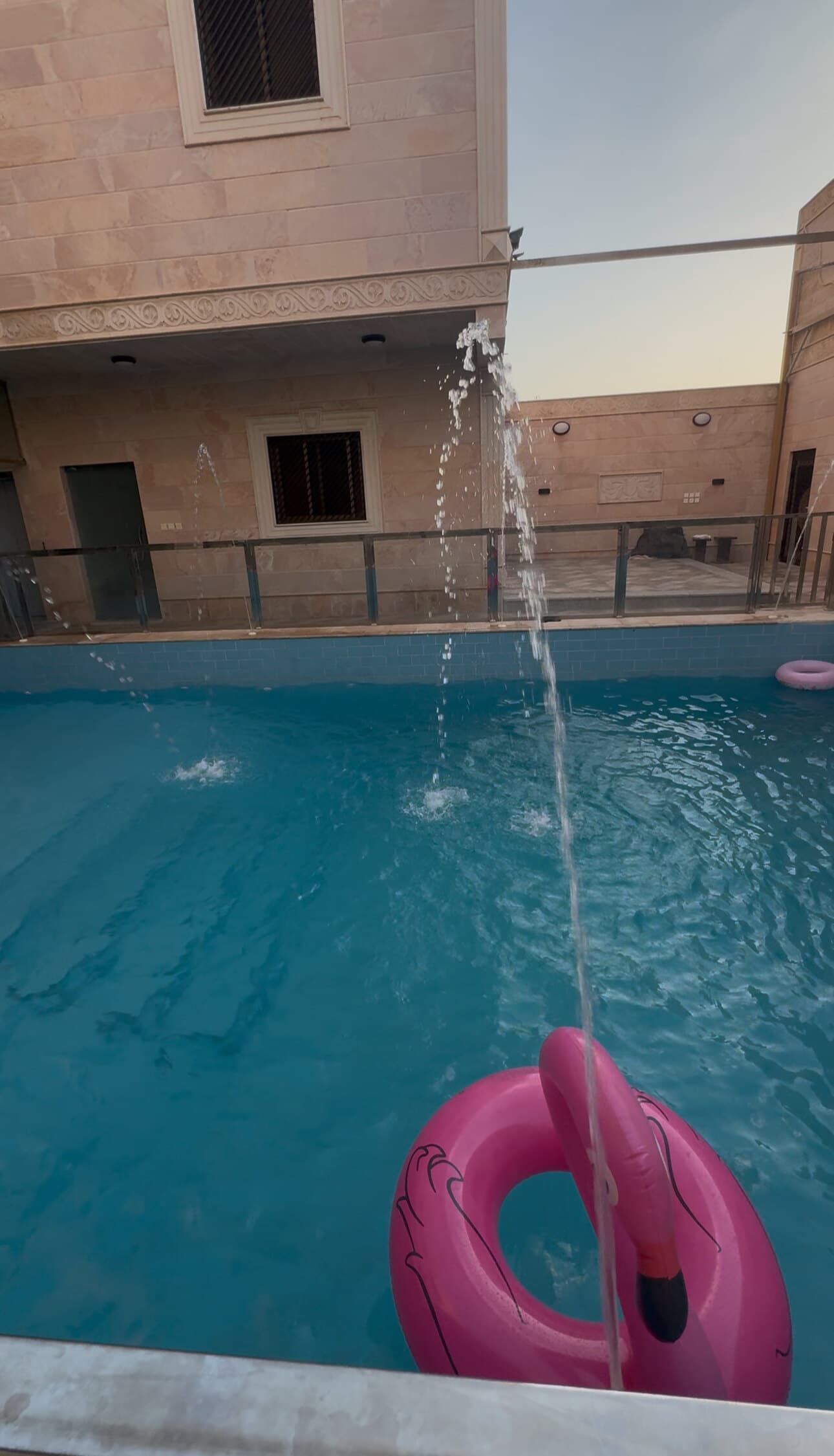 Le jet d'eau du bassin, dans la cour, au crépuscule