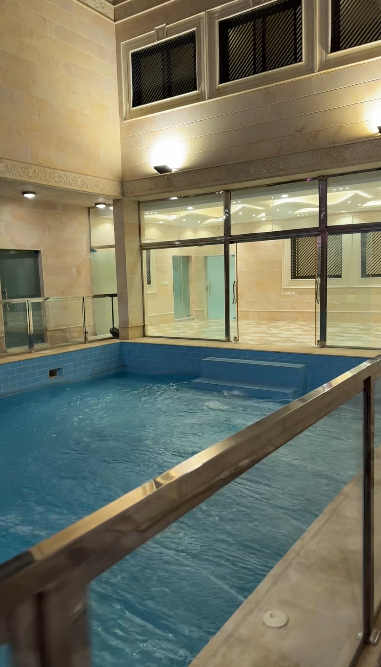 La piscine le soir, vue depuis les baies vitrées de la villa